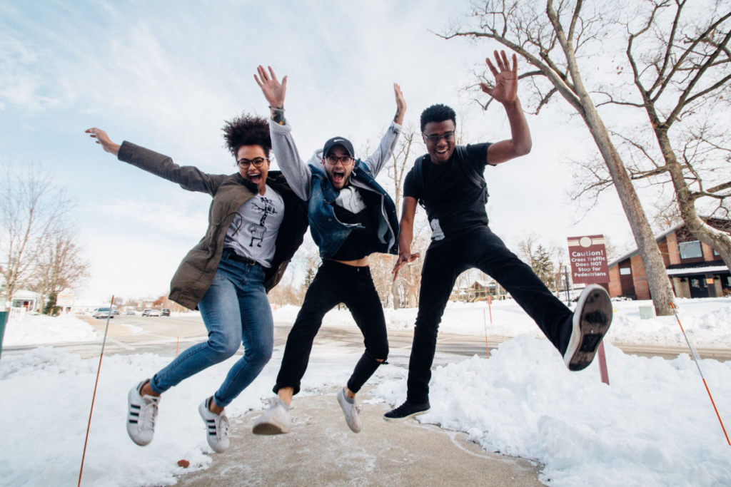 group of young influencers smiling and jumping into the air together with snow on the ground