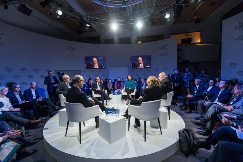 People seated on a circular stage discussing important matters.