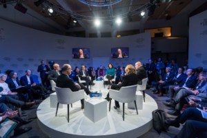 People seated on a circular stage discussing important matters.